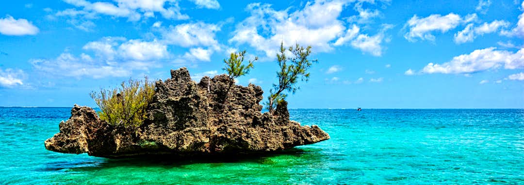 Urlaubsziel Mauritius – Paradiesischer Strand von Mauritius mit Palmen und Berg Le Morne im Hintergrund