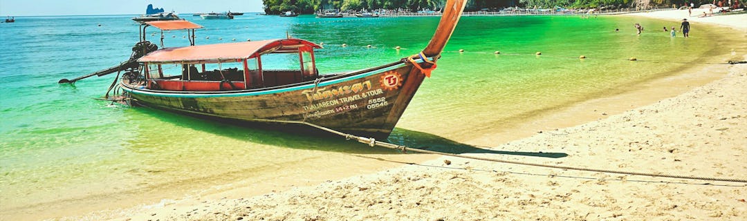 Traditionelles Longtail-Boot vor dramatischen Kalksteinfelsen in der Andamanensee, Thailand