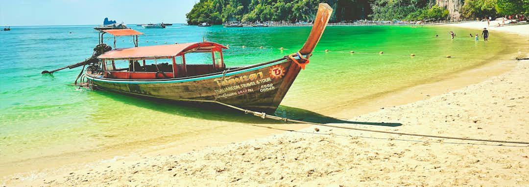 Urlaubsziel Thailand – Traditionelles Longtail-Boot vor dramatischen Kalksteinfelsen in der Andamanensee, Thailand
