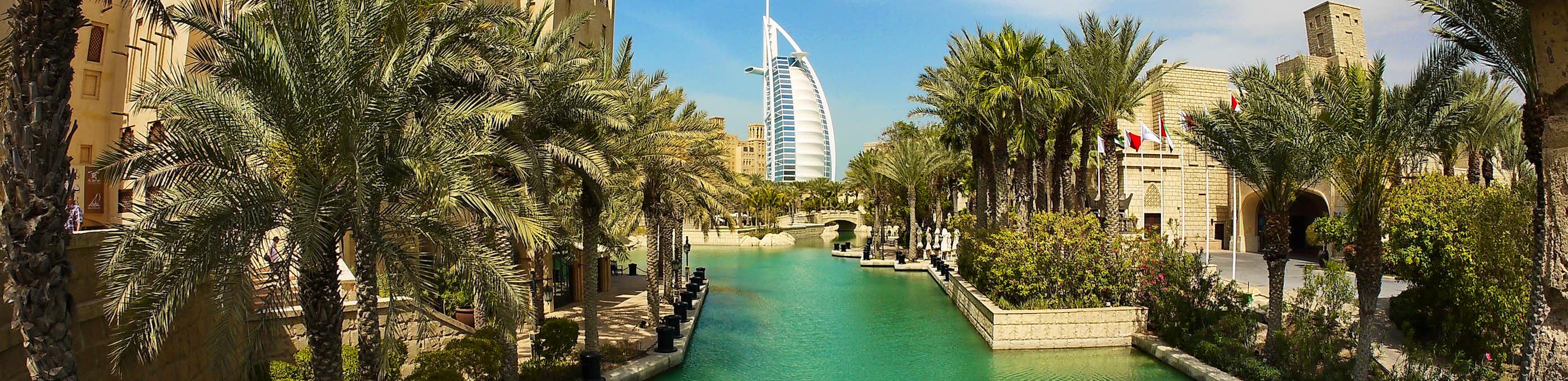 Luxuriöser Wasserkanal in Dubai mit modernen Wolkenkratzern, traditionellen arabischen Booten und beleuchteten Promenaden bei Sonnenuntergang