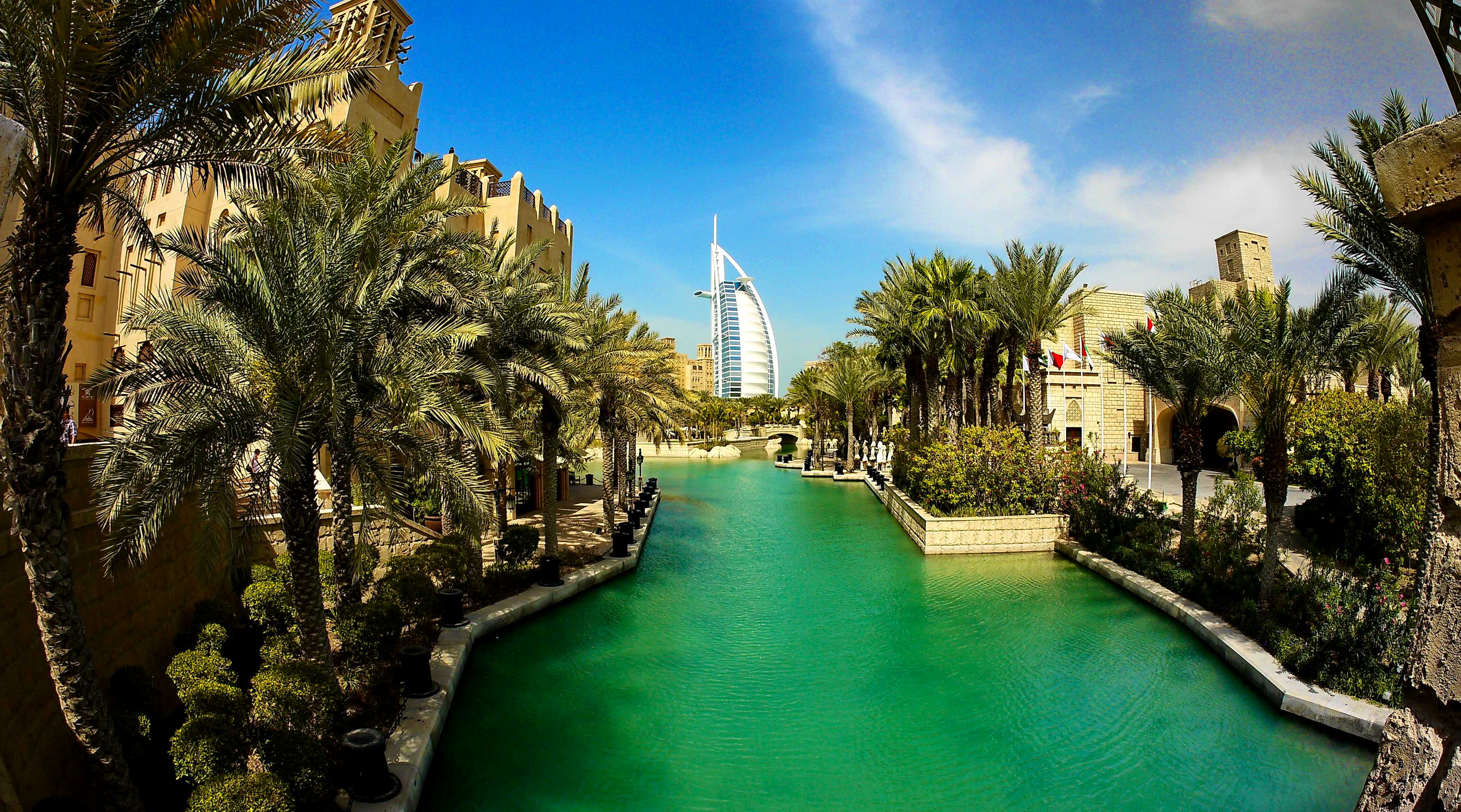 Luxuriöser Wasserkanal in Dubai mit modernen Wolkenkratzern, traditionellen arabischen Booten und beleuchteten Promenaden bei Sonnenuntergang